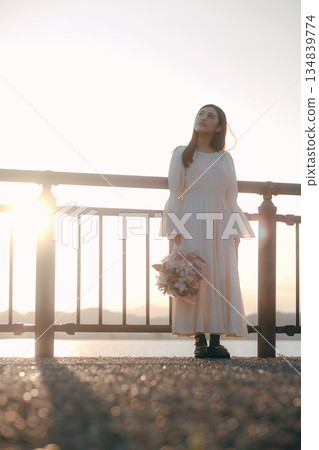 A Japanese woman standing with dried flowers in the background of the sea 134839774