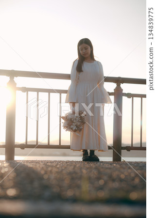 A Japanese woman standing with dried flowers in the background of the sea 134839775