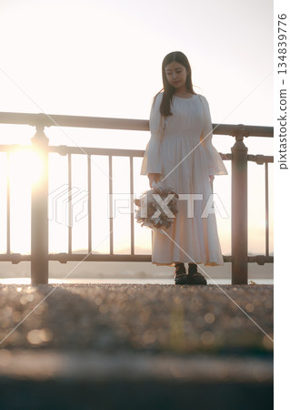 A Japanese woman standing with dried flowers in the background of the sea 134839776