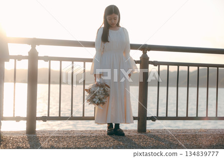 一位日本女子手捧乾花,站在海邊。 一位日本女子手捧乾花,站在海邊。 134839777