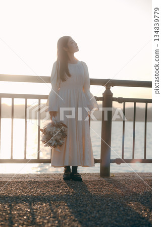 一位日本女子手捧乾花,站在海邊。 一位日本女子手捧乾花,站在海邊。 134839779