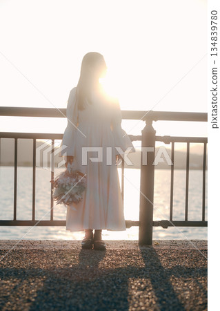 A Japanese woman standing with dried flowers in the background of the sea A Japanese woman standing with dried flowers in the background of the sea 134839780