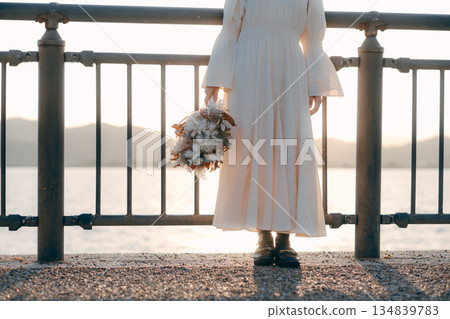 A Japanese woman standing with dried flowers in the background of the sea A Japanese woman standing with dried flowers in the background of the sea 134839783