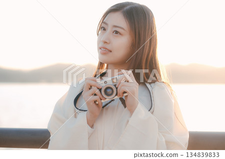 一位日本女子在海灘上拿著一台底片相機 一位日本女子在海灘上拿著一台底片相機 134839833