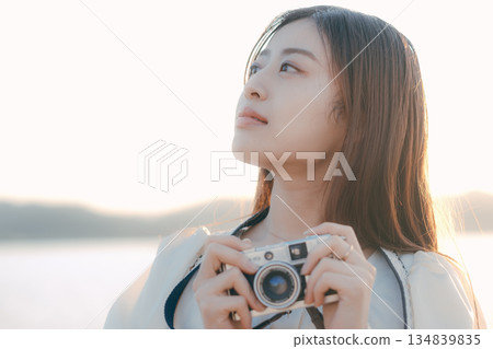 一位日本女子在海灘上拿著一台底片相機 一位日本女子在海灘上拿著一台底片相機 134839835