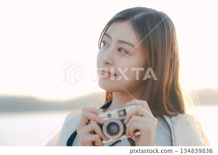 Japanese woman holding a film camera at the beach Japanese woman holding a film camera at the beach 134839836
