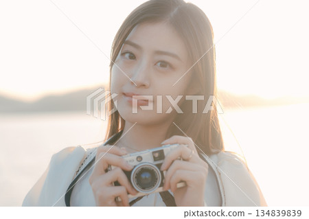 Japanese woman holding a film camera at the beach Japanese woman holding a film camera at the beach 134839839