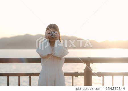 一位日本女子在海灘上拿著一台底片相機 134839844
