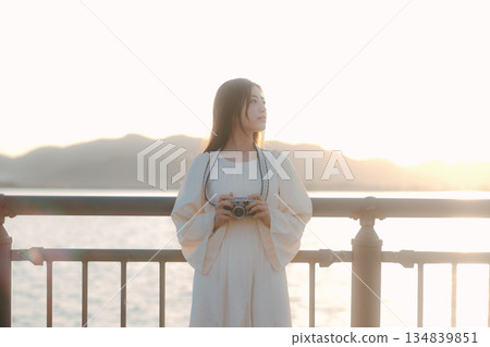 一位日本女子在海灘上拿著一台底片相機 一位日本女子在海灘上拿著一台底片相機 134839851