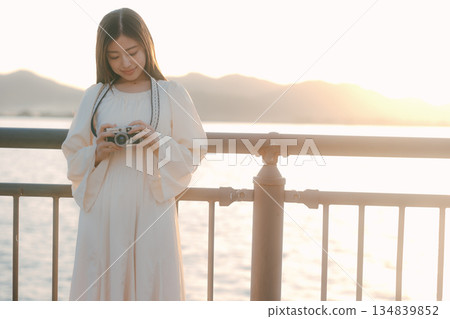 一位日本女子在海灘上拿著一台底片相機 一位日本女子在海灘上拿著一台底片相機 134839852