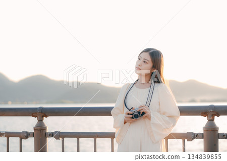 Japanese woman holding a film camera at the beach Japanese woman holding a film camera at the beach 134839855