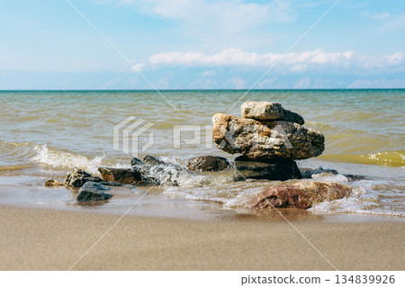 Rock formation on a sandy beach shore with calm ocean waves rolling in Rock formation on a sandy beach shore with calm ocean waves rolling in 134839926