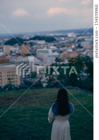 一位日本女性背對著鏡頭，用智慧型手機拍攝城市景觀。 134839968