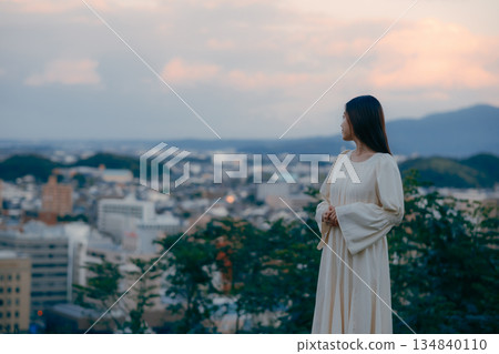 一位日本女性站在城市景觀前，背景是城市風景。 134840110