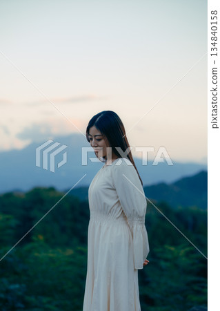 一位日本女性站在山前，背景是一座山。 134840158