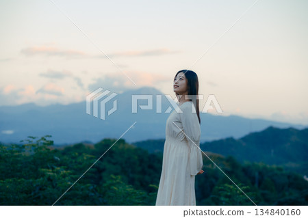 一位日本女性站在山前，背景是一座山。 134840160