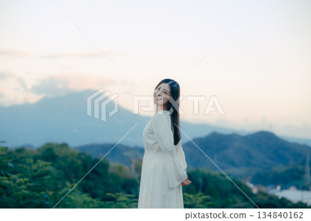一位日本女性站在山前，背景是一座山。 134840162