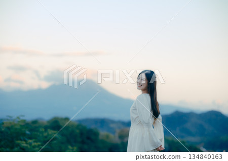 一位日本女性站在山前，背景是一座山。 134840163