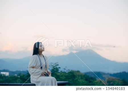 一位日本女子手持底片相機，背景是連綿的山脈。 134840183