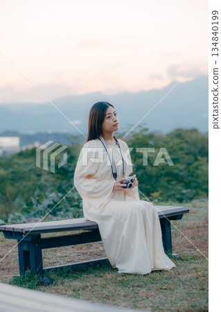 一位日本女子手持電影相機,背景是城市景觀。 一位日本女子手持電影相機,背景是城市景觀。 134840199
