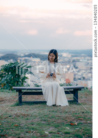 一位日本女子手持電影相機,背景是城市景觀。 一位日本女子手持電影相機,背景是城市景觀。 134840205