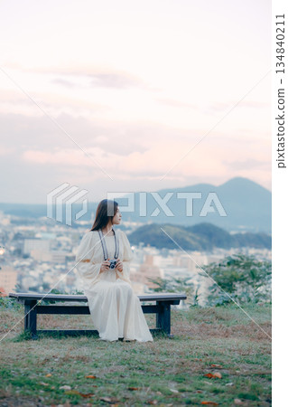 一位日本女子手持電影相機,背景是城市景觀。 一位日本女子手持電影相機,背景是城市景觀。 134840211