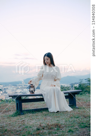 一位日本婦女將燈籠放在俯瞰城市的山丘上 134840308