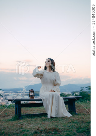 一位日本婦女將燈籠放在俯瞰城市的山丘上 一位日本婦女將燈籠放在俯瞰城市的山丘上 134840309