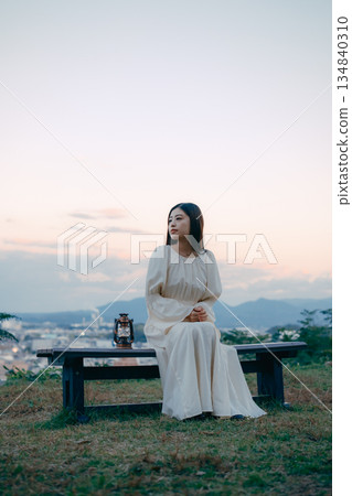 A Japanese woman placing a lantern on a hill overlooking the city A Japanese woman placing a lantern on a hill overlooking the city 134840310
