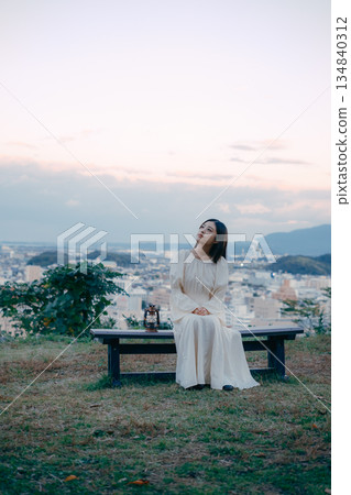 A Japanese woman placing a lantern on a hill overlooking the city 134840312