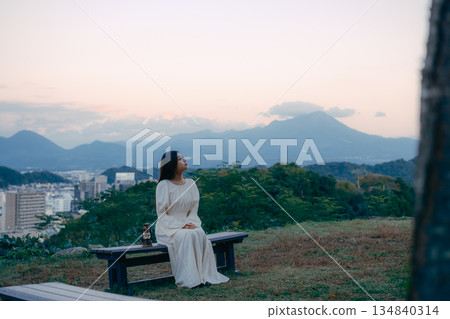 A Japanese woman placing a lantern on a hill overlooking the city 134840314