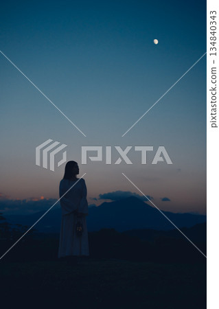 夕陽西下，月亮升起，一位女子的身影佇立在山間。 134840343