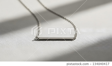 Elegant Silver Necklace With Minimalist Bar Pendant on White Textured Surface 134840417