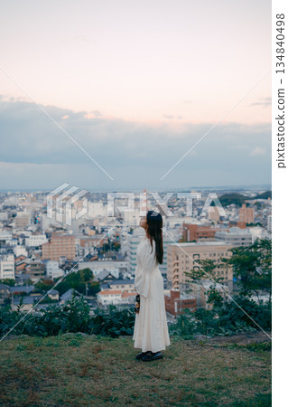 A woman holding a lantern on a hill overlooking the city A woman holding a lantern on a hill overlooking the city 134840498