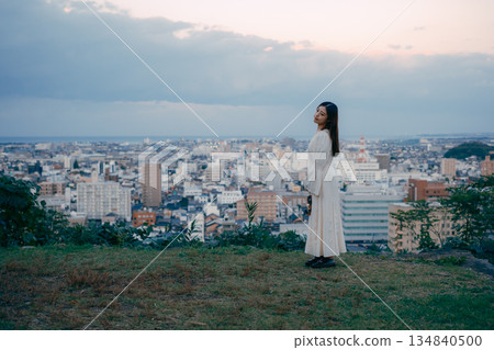 一位女子在俯瞰城市的山丘上提著燈籠 134840500