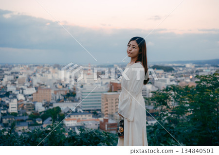 一位女子在俯瞰城市的山丘上提著燈籠 134840501