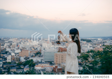 一位女子在俯瞰城市的山丘上提著燈籠 134840503