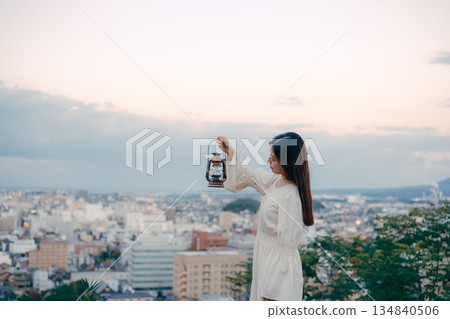 一位女子在俯瞰城市的山丘上提著燈籠 134840506