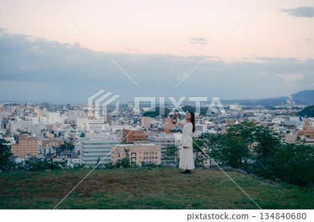 一位女子在俯瞰城市的山丘上提著燈籠 134840680