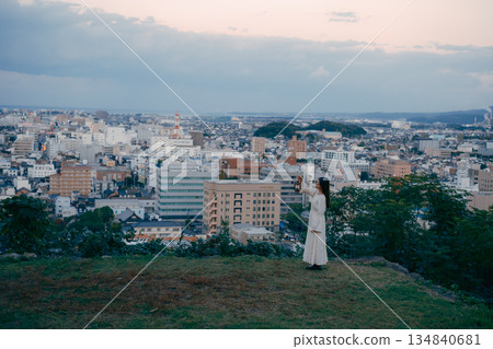 一位女子在俯瞰城市的山丘上提著燈籠 134840681