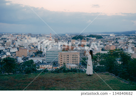 A woman holding a lantern on a hill overlooking the city 134840682