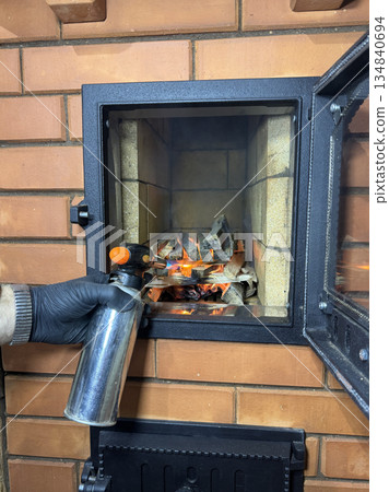 Worker lights a test fire in the stove firebox. Using a torch and a gas canister. 134840694
