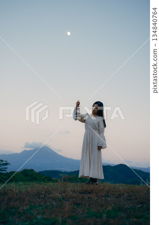 A woman standing with a lantern at sunset in the mountains A woman standing with a lantern at sunset in the mountains 134840764