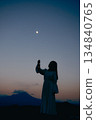夕陽西下，月亮升起，一位女子的身影佇立在山間。 134840765