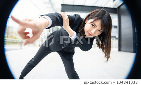 一位女商人指著前方。魚眼鏡頭突顯了挑戰與未來的意象。她是日本商業區裡的女性。 134841338