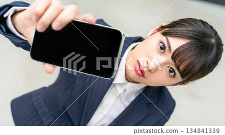 Close-up of a businesswoman presenting a smartphone screen. App introduction and digital utilization image. Copy space. 134841339