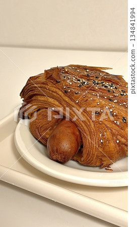 Flaky golden croissant filled with savory sausage, combining buttery layers of pastry with rich, meaty flavor for a satisfying and hearty snack or breakfast item 134841994