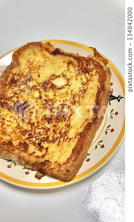 Golden, fluffy French toast with a crisp edge and soft center, topped with syrup, fruits, or powdered sugar. Offering a perfect balance of sweetness, warmth, and comfort in every delightful bite. 134842000