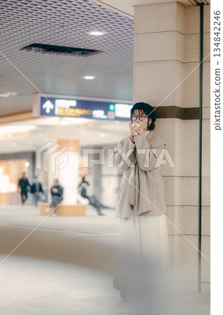 Full-body portrait of a woman in her 30s drinking coffee while waiting 134842246