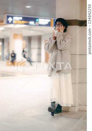 Full-body portrait of a woman in her 30s drinking coffee while waiting Full-body portrait of a woman in her 30s drinking coffee while waiting 134842250